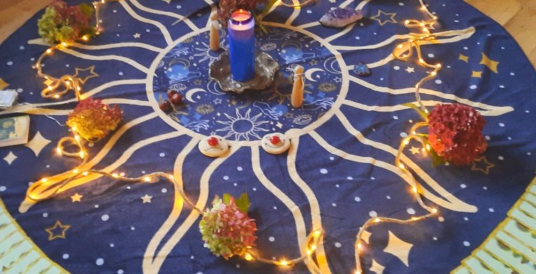Astrologischer Rundteppich mit einer Lichterkette im Kreis. Am Rand liegen viele verdeckte Karten.